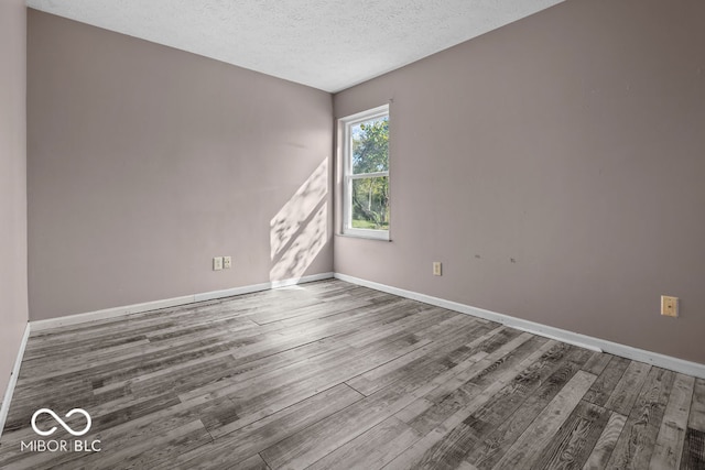 spare room with a textured ceiling and wood-type flooring