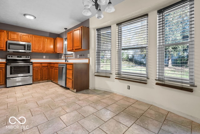 kitchen with decorative light fixtures, appliances with stainless steel finishes, a chandelier, and a healthy amount of sunlight