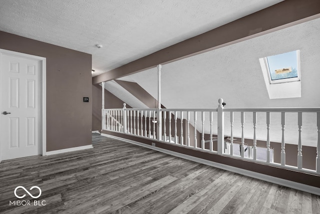 interior space featuring a skylight, hardwood / wood-style flooring, beam ceiling, and a textured ceiling