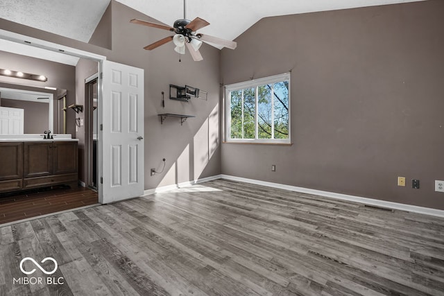 interior space with wood-type flooring, sink, high vaulted ceiling, connected bathroom, and ceiling fan