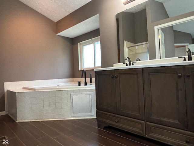 bathroom featuring vanity, wood-type flooring, a textured ceiling, shower with separate bathtub, and vaulted ceiling