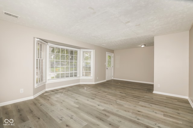 empty room with wood-type flooring and a textured ceiling