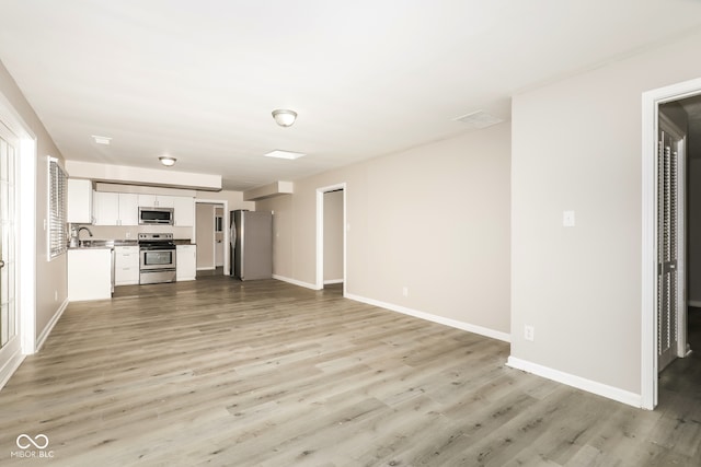 unfurnished living room featuring light hardwood / wood-style flooring and sink