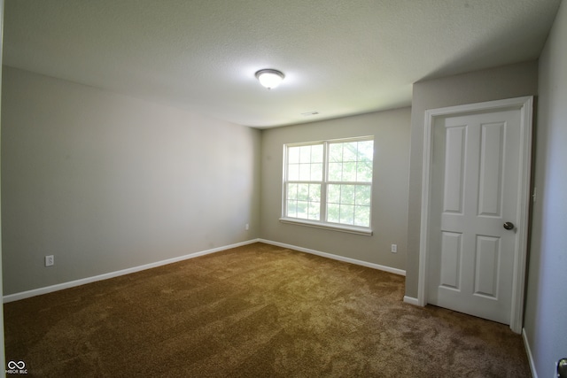 unfurnished room featuring dark colored carpet and a textured ceiling