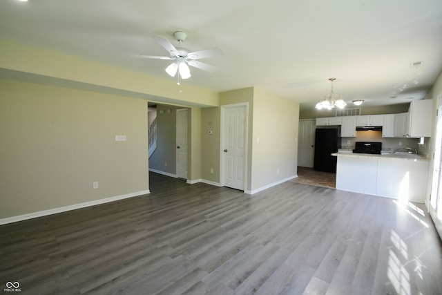 kitchen with white cabinets, hardwood / wood-style flooring, ceiling fan with notable chandelier, kitchen peninsula, and black fridge