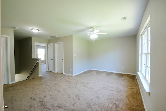 spare room with ceiling fan and light colored carpet