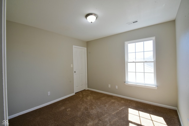 spare room with dark carpet