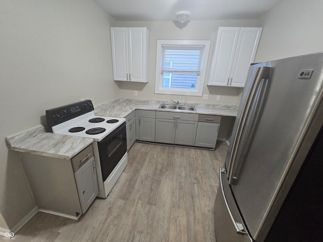 kitchen featuring stainless steel refrigerator, white cabinetry, sink, and electric range