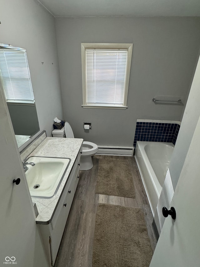 bathroom featuring a baseboard heating unit, a washtub, hardwood / wood-style floors, toilet, and vanity