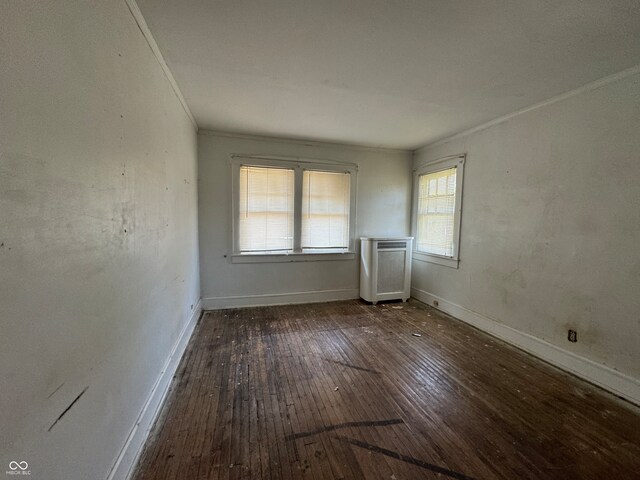 unfurnished room featuring radiator heating unit, a wealth of natural light, and dark hardwood / wood-style floors