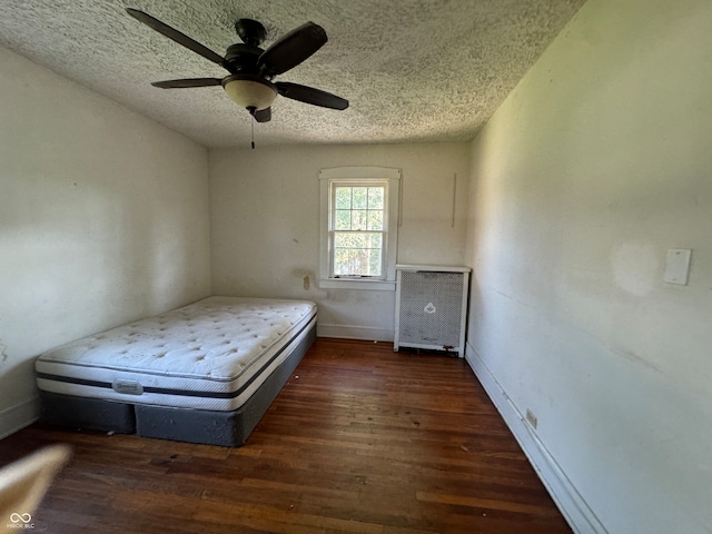 unfurnished bedroom featuring a textured ceiling, dark hardwood / wood-style flooring, and ceiling fan