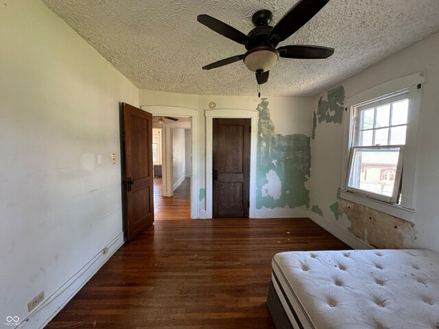 unfurnished bedroom featuring ceiling fan, radiator, a textured ceiling, and dark hardwood / wood-style flooring