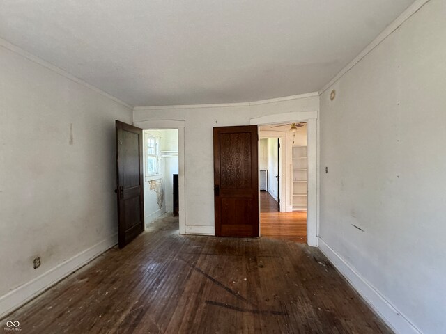 unfurnished room featuring ceiling fan, crown molding, and dark wood-type flooring