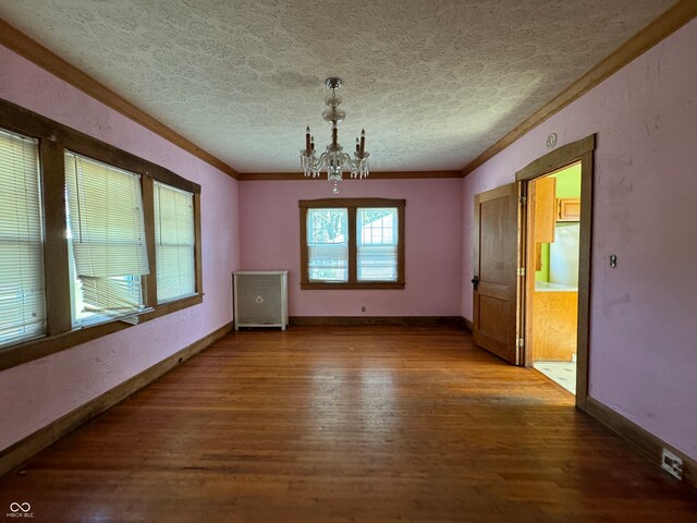 unfurnished dining area with hardwood / wood-style flooring, crown molding, a chandelier, and a textured ceiling