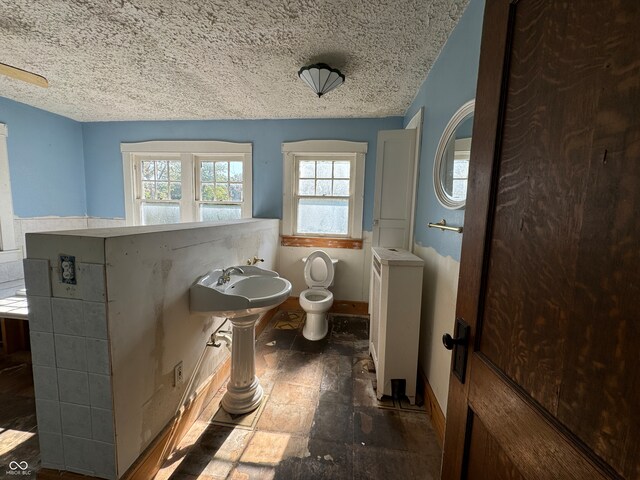 bathroom featuring a textured ceiling, toilet, and sink