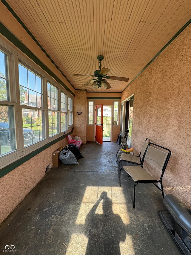 unfurnished sunroom with ceiling fan, plenty of natural light, and wooden ceiling