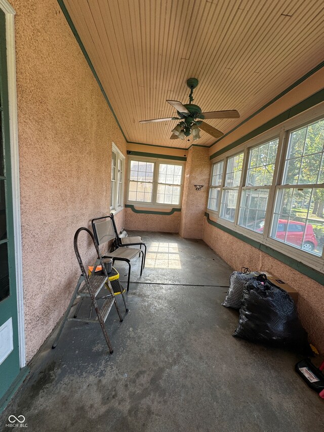 unfurnished sunroom featuring wood ceiling and ceiling fan