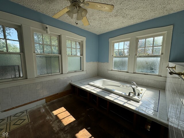 bathroom with tile walls, ceiling fan, plenty of natural light, and a tub