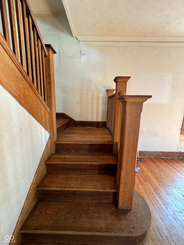 stairway with hardwood / wood-style flooring and a textured ceiling