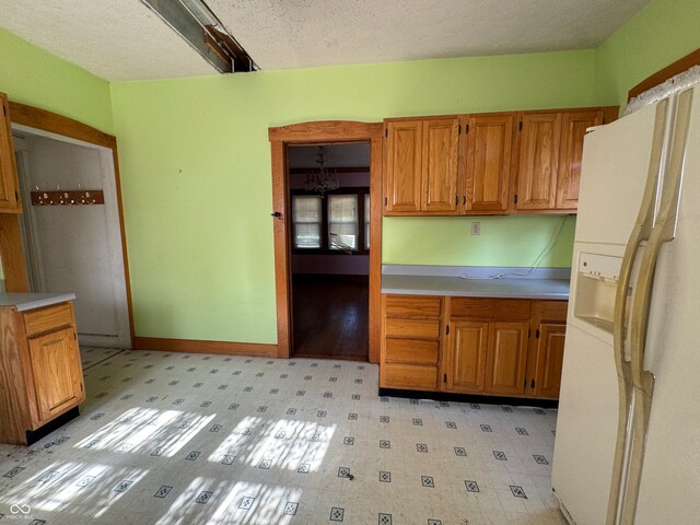 kitchen featuring a textured ceiling and white refrigerator with ice dispenser