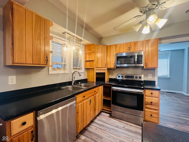 kitchen with ceiling fan, stainless steel appliances, sink, and light hardwood / wood-style flooring