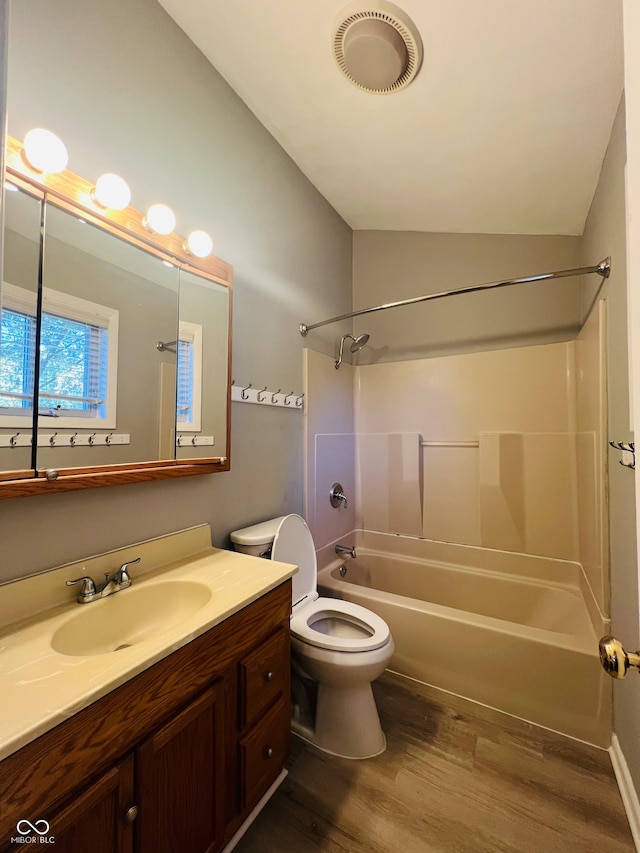 full bathroom featuring vanity, lofted ceiling, hardwood / wood-style flooring, bathing tub / shower combination, and toilet