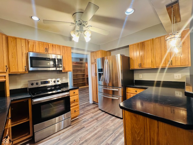 kitchen with light wood-type flooring, ceiling fan, stainless steel appliances, and decorative light fixtures