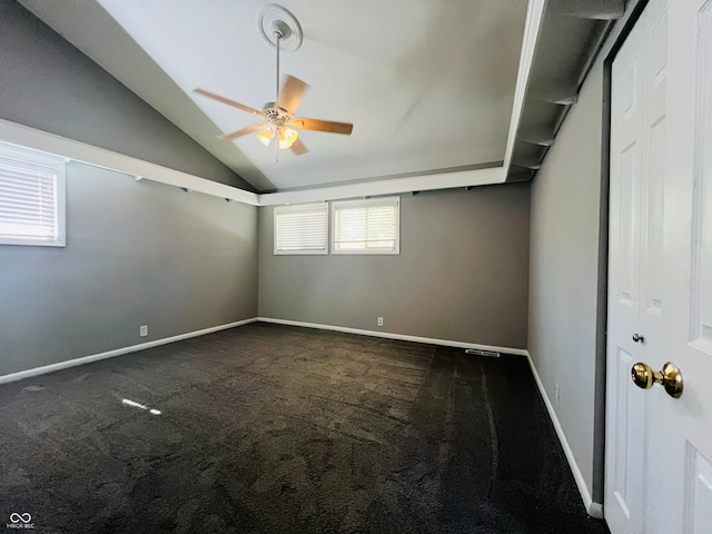 carpeted spare room featuring vaulted ceiling and ceiling fan