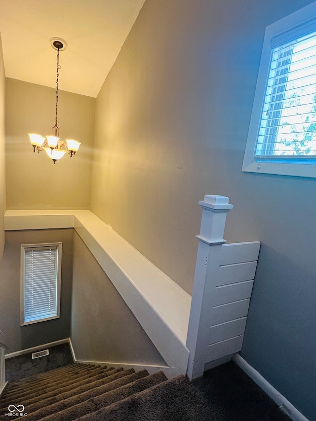 stairs with a notable chandelier, lofted ceiling, and carpet flooring