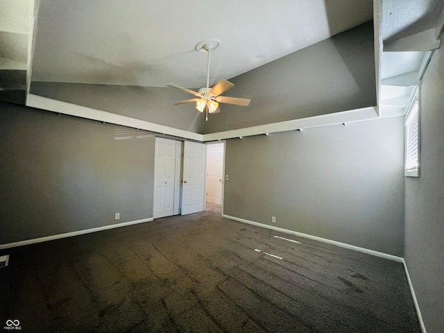 unfurnished bedroom with ceiling fan, dark carpet, and high vaulted ceiling