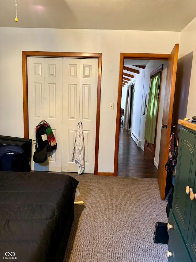 bedroom with a closet, hardwood / wood-style floors, and a baseboard heating unit