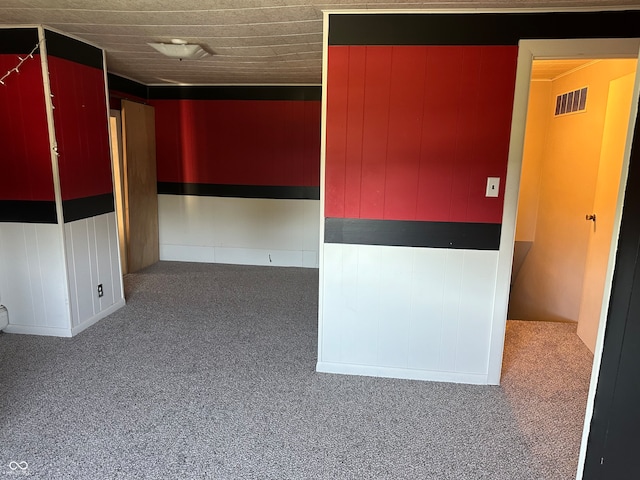 spare room featuring carpet floors and wooden walls