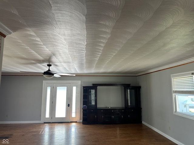 unfurnished living room with crown molding, ceiling fan, and dark wood-type flooring