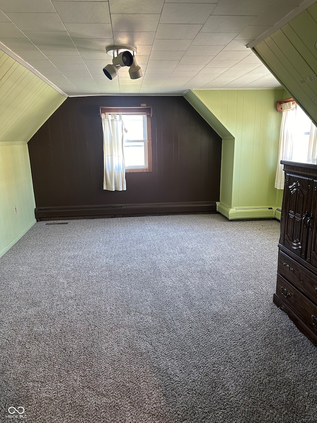 bonus room with light carpet, wooden walls, and vaulted ceiling