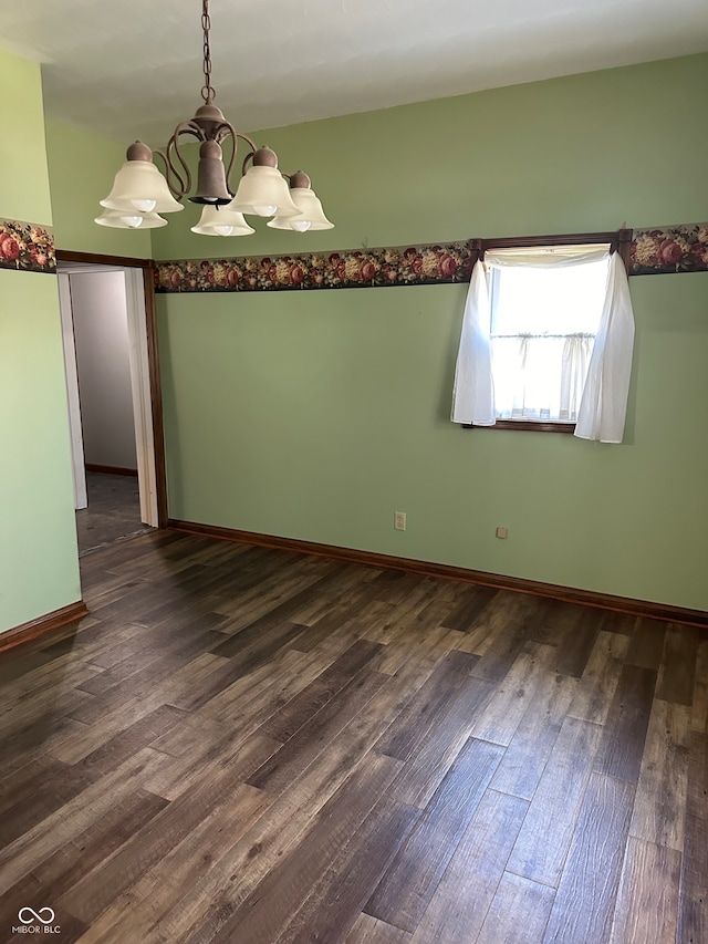 empty room featuring dark hardwood / wood-style flooring and a notable chandelier