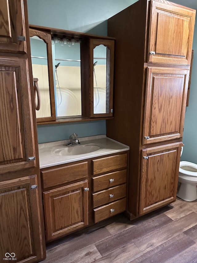 bathroom featuring hardwood / wood-style floors, vanity, toilet, and a shower