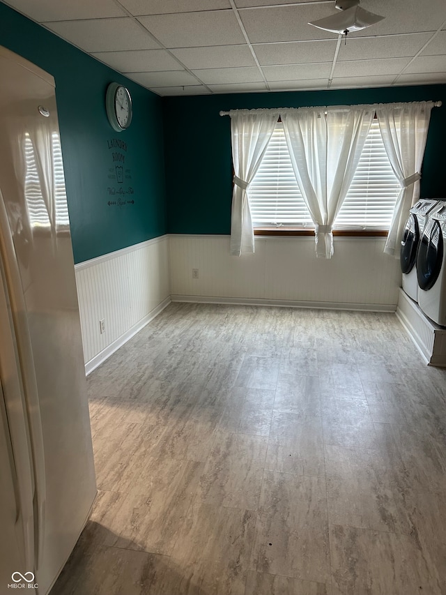 unfurnished room featuring a drop ceiling, ceiling fan, independent washer and dryer, and hardwood / wood-style flooring