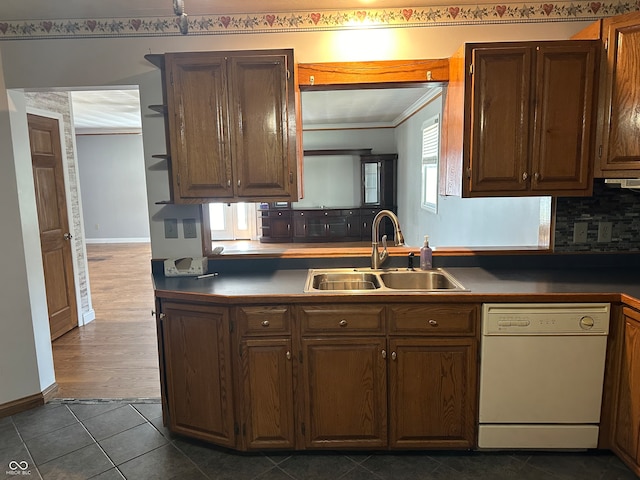 kitchen with dark tile patterned flooring, sink, backsplash, dishwasher, and crown molding