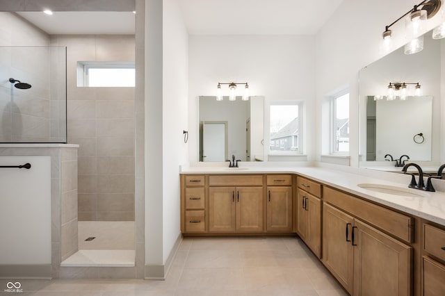 bathroom featuring tiled shower, vanity, and tile patterned flooring