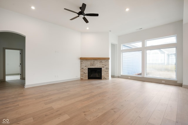 unfurnished living room with ceiling fan, a fireplace, and light hardwood / wood-style flooring