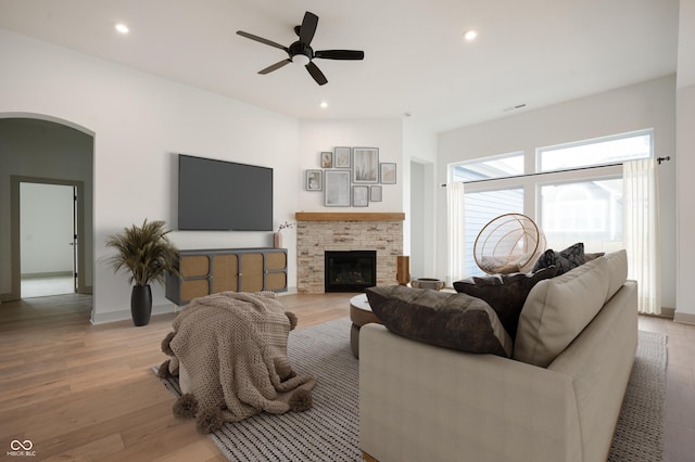 living room with ceiling fan, a fireplace, and light hardwood / wood-style floors