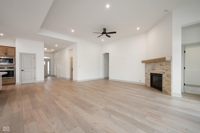 unfurnished living room with ceiling fan, a fireplace, and light hardwood / wood-style flooring