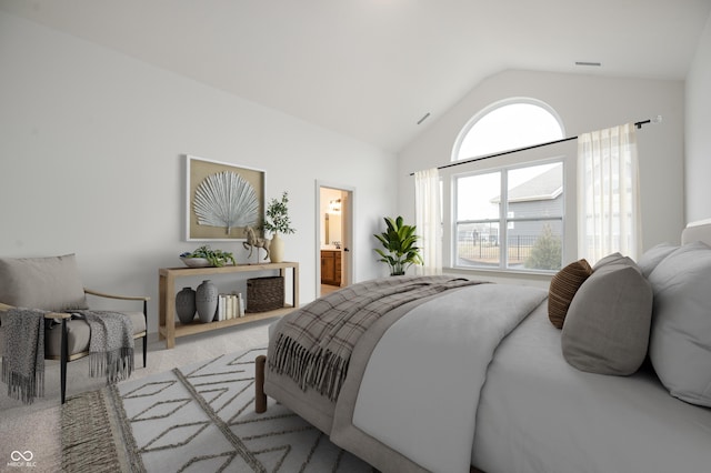 bedroom featuring light colored carpet, lofted ceiling, and connected bathroom