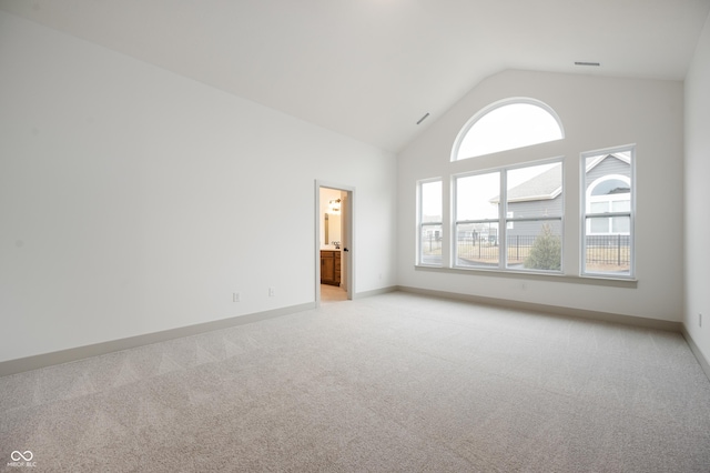 carpeted empty room with high vaulted ceiling