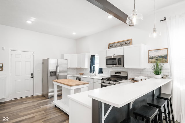 kitchen with a breakfast bar, white cabinets, light hardwood / wood-style flooring, appliances with stainless steel finishes, and decorative light fixtures