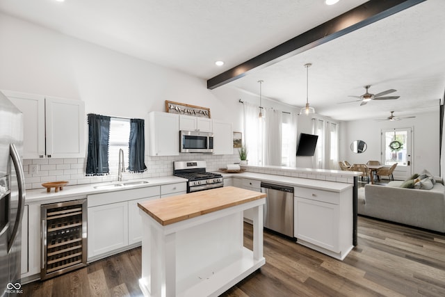 kitchen with appliances with stainless steel finishes, a center island, white cabinetry, and beverage cooler