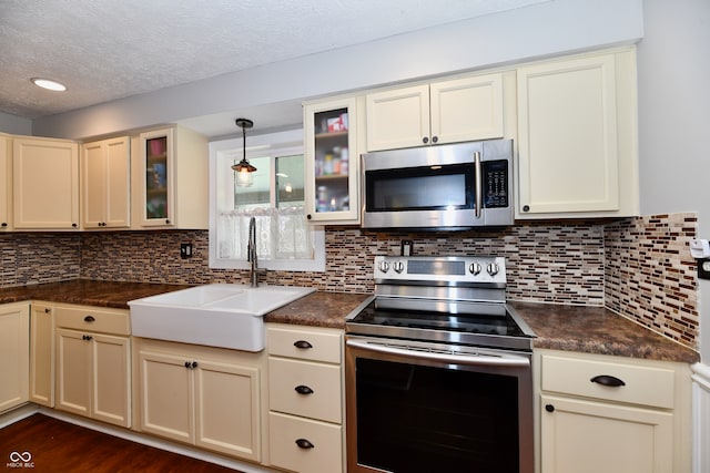 kitchen featuring stainless steel appliances, sink, hanging light fixtures, and cream cabinetry