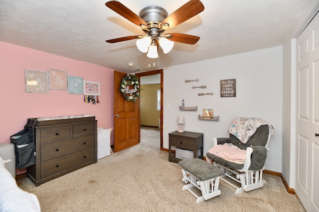 sitting room with a textured ceiling, light colored carpet, and ceiling fan