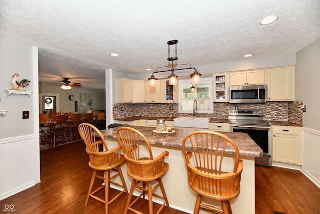 kitchen featuring sink, a kitchen breakfast bar, kitchen peninsula, stainless steel appliances, and dark wood-type flooring