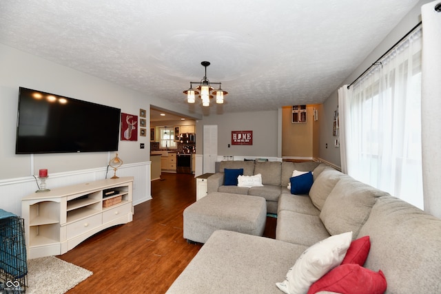 living room with dark wood-type flooring, a chandelier, and a textured ceiling